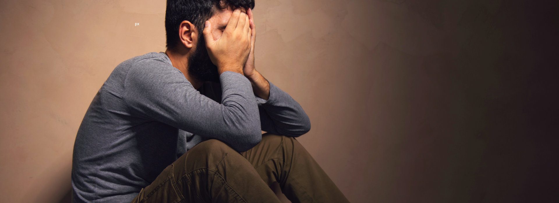 Man zit voorovergebogen met zijn handen voor zijn gezicht. 