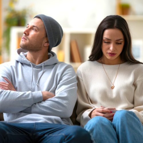 Man en vrouw zitten gespannen naast elkaar, beeld bij relatieproblemen en emotionele afstand