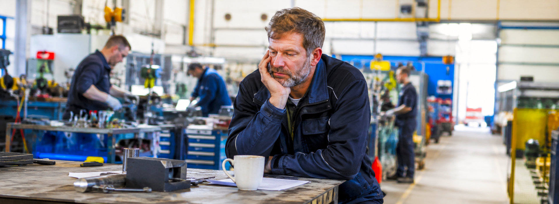 Medewerker op een brede werkvloer met vermoeide blik, passend bij mentale mist en haperende motivatie op het werk.