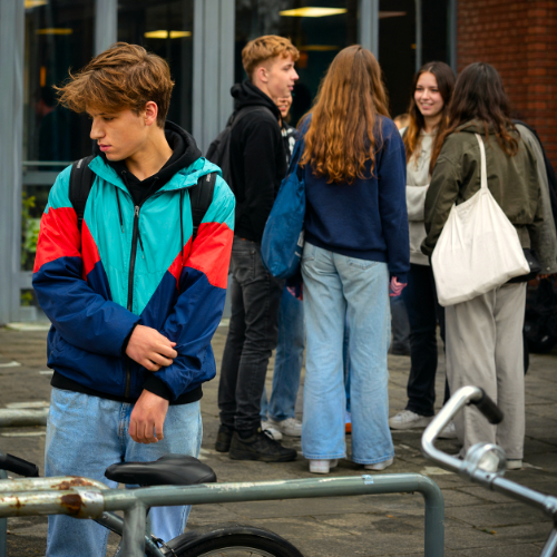 Jongere staat onzeker apart van een groep leeftijdsgenoten bij school of opleiding