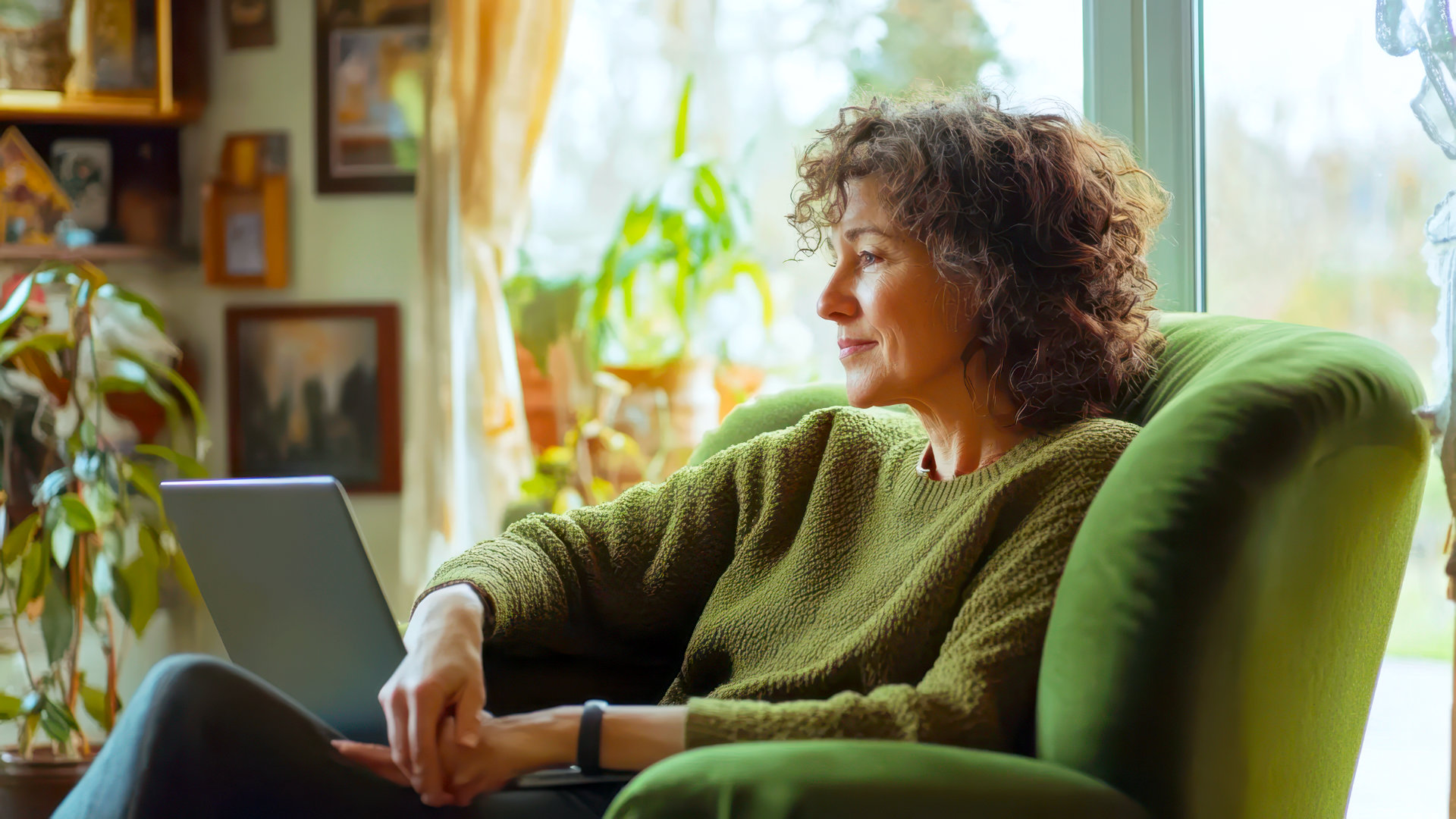 Vrouw met laptop in een groene fauteuil voor online coaching vanuit huis