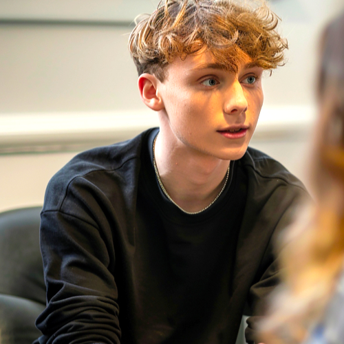 Jonge man luistert aandachtig in gesprek in een rustige setting als beeld bij jongerencoaching.