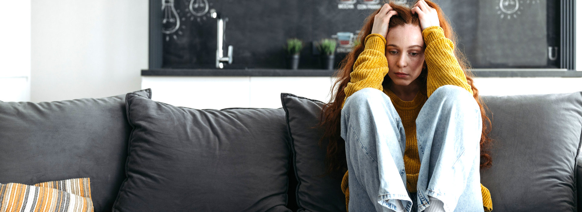 Vrouw zit uitgeput en overbelast op de bank, beeld bij burn-out coaching en therapie bij Spreek met Freek.