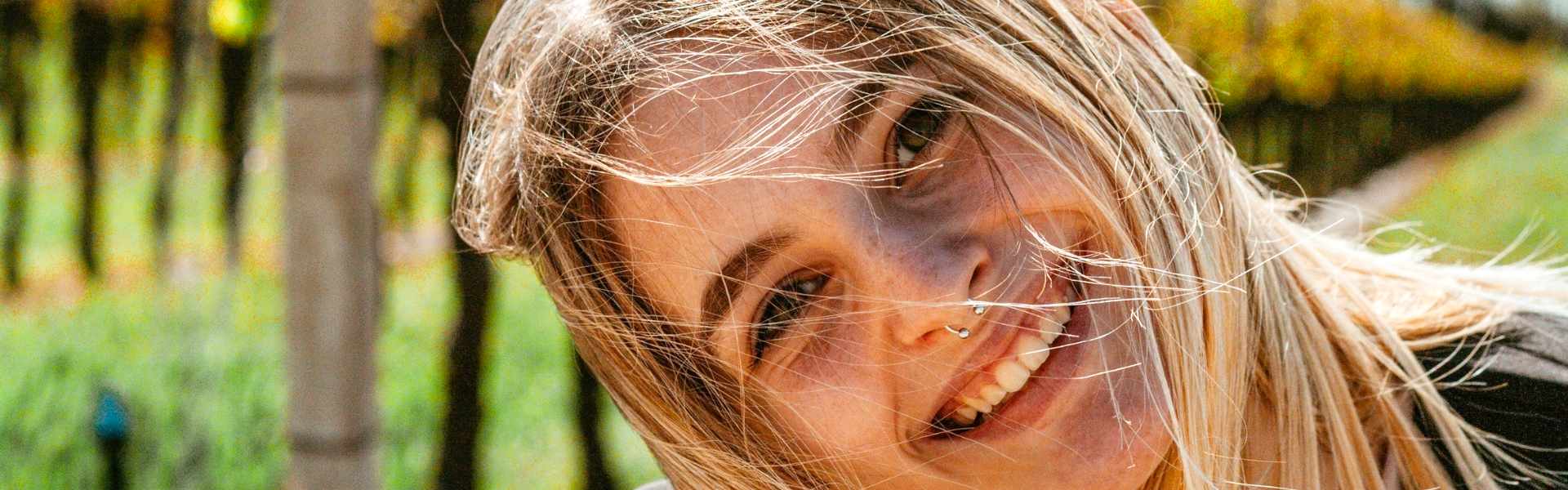 Vrouw kijkt met een open glimlach naar voren, beeld bij coaching rond persoonlijke groei, bewuster kiezen en meer ruimte innemen bij Spreek met Freek.