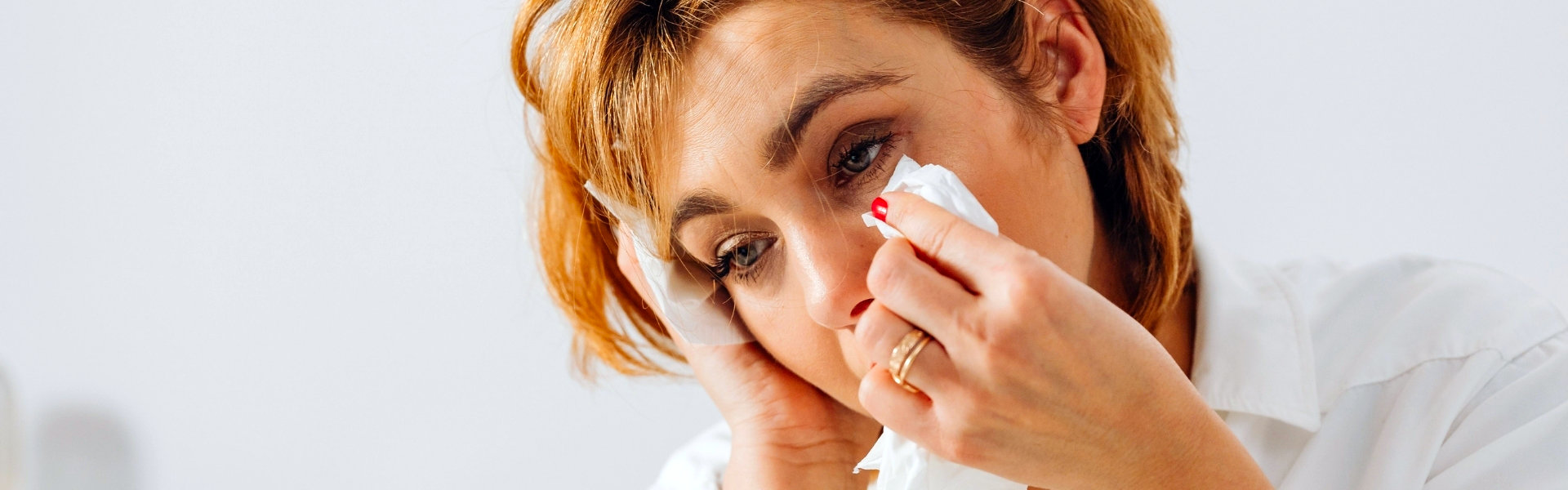 Vrouw veegt haar tranen weg met een tissue, beeld bij rouwtherapie over verlies, verdriet en verwerking bij Spreek met Freek.